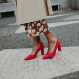 Woman wearing Luna Selene red high-heeled shoes on a sidewalk