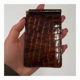 Hand holding Luna Selene brown money clip wallet and putting money into it. 