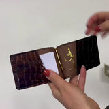Hand holding Luna Selene brown money clip wallet and putting money into it. 